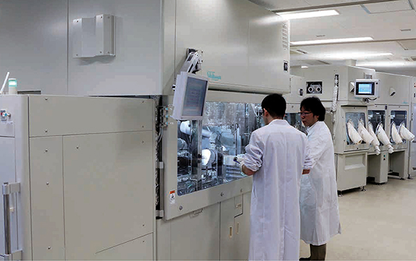 Two lab technicians working with a machine.