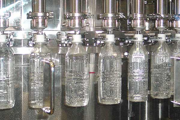 A collection of bottles being filled with water.