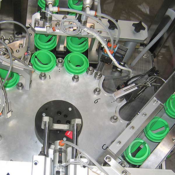 A collection of plastic caps for glue being produced in a machine.