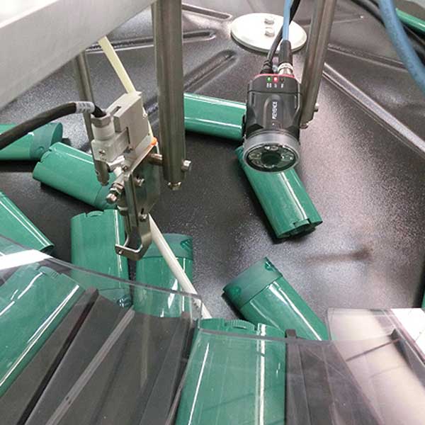 Plastic deodorant containers being processed in a machine.