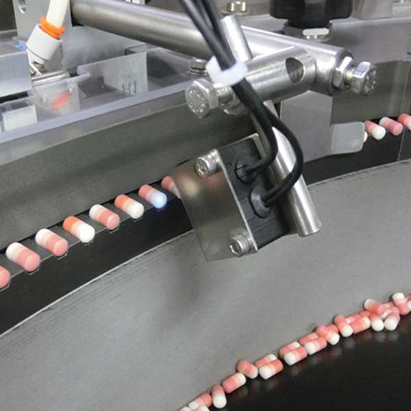 A tablet feeder machine with a sensor above each tablet.
